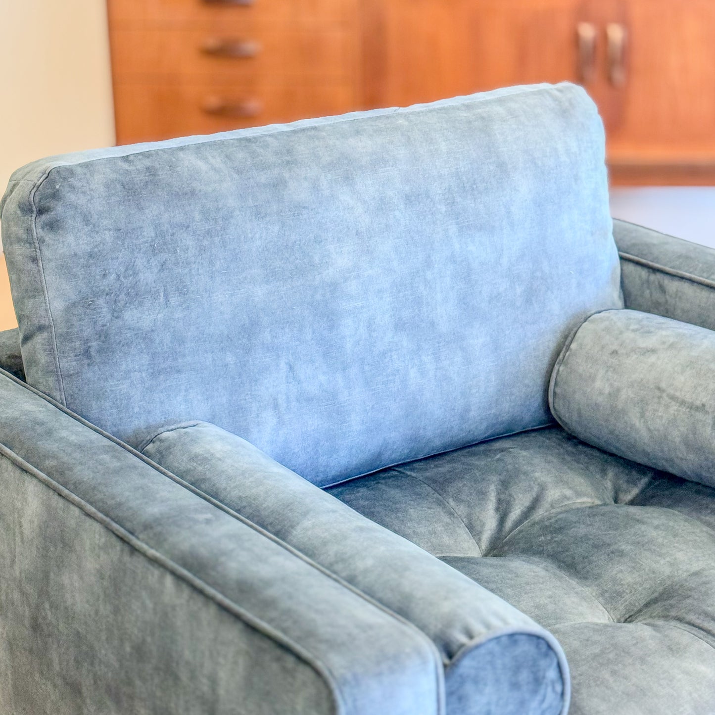 Blue suede armchair with loose bolster cushions